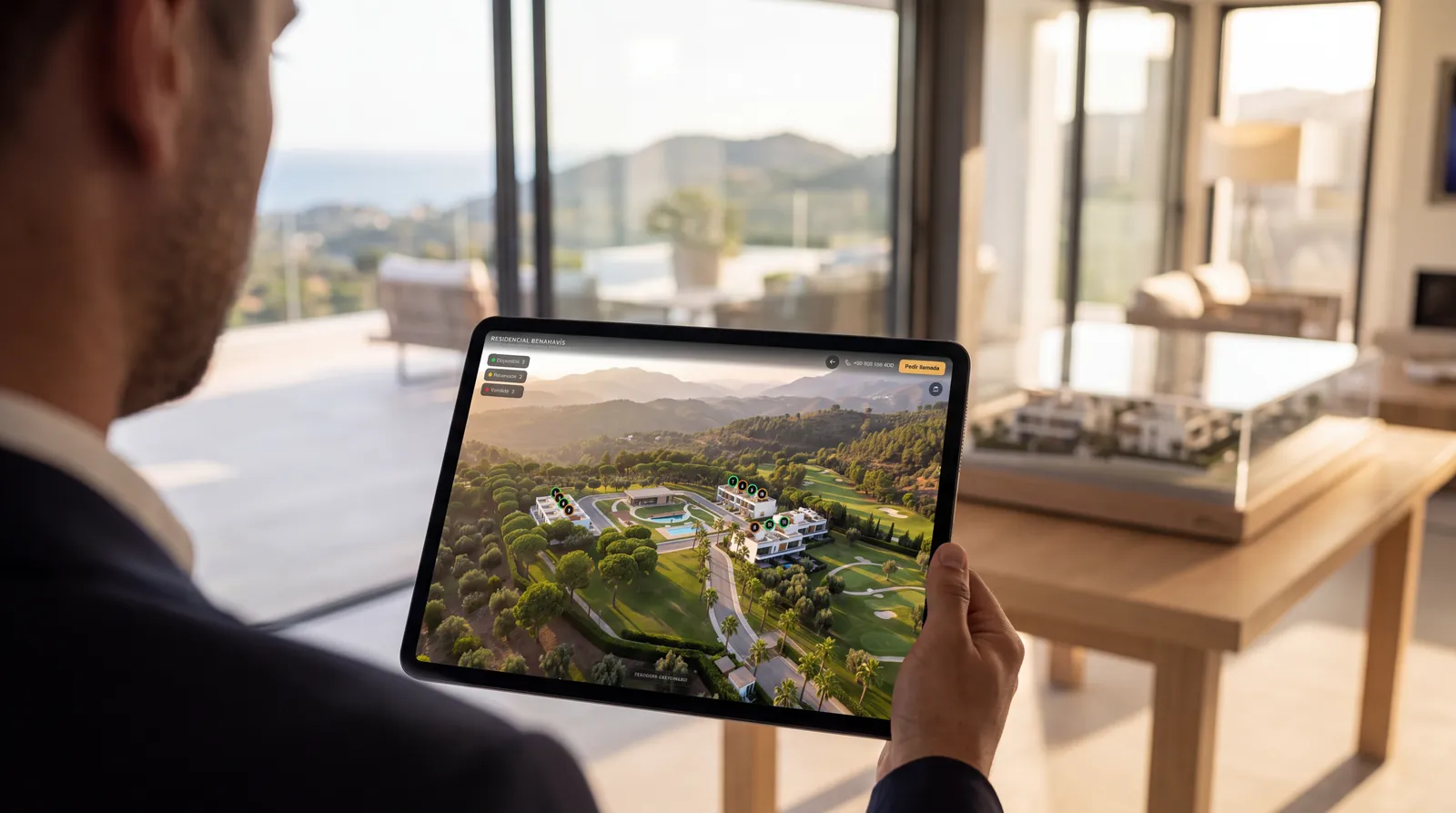 Un comercial sostiene una tablet con el masterplan de la promoción en una sala de ventas con vistas al mar (imagen ilustrativa)